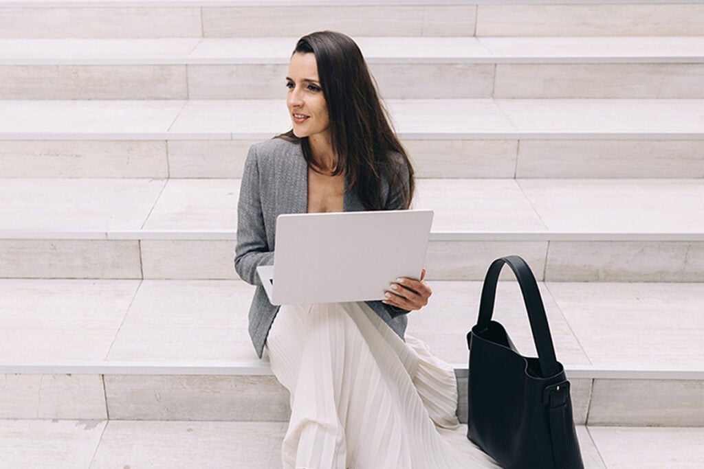 Professional woman on steps with laptop and black bag