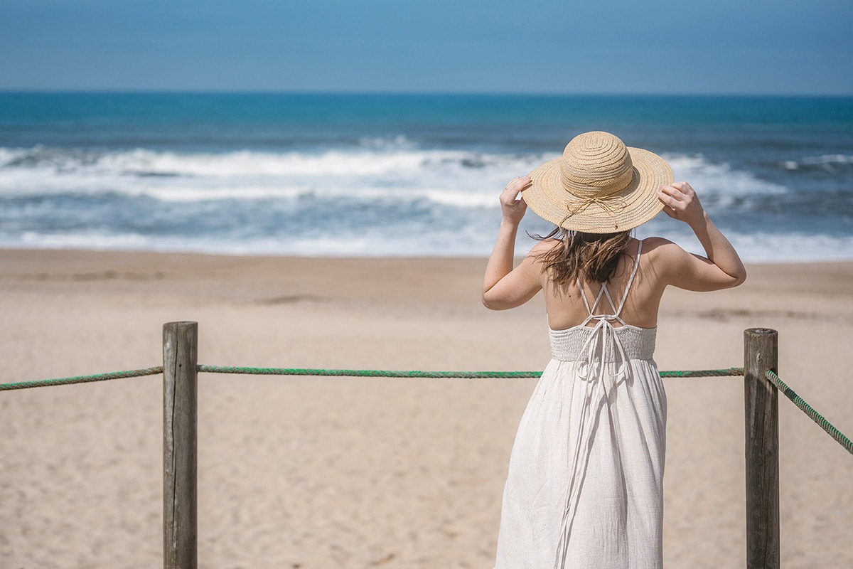 Time for a Change 5 | Woman in white dress and straw hat looking out across beach and ocean