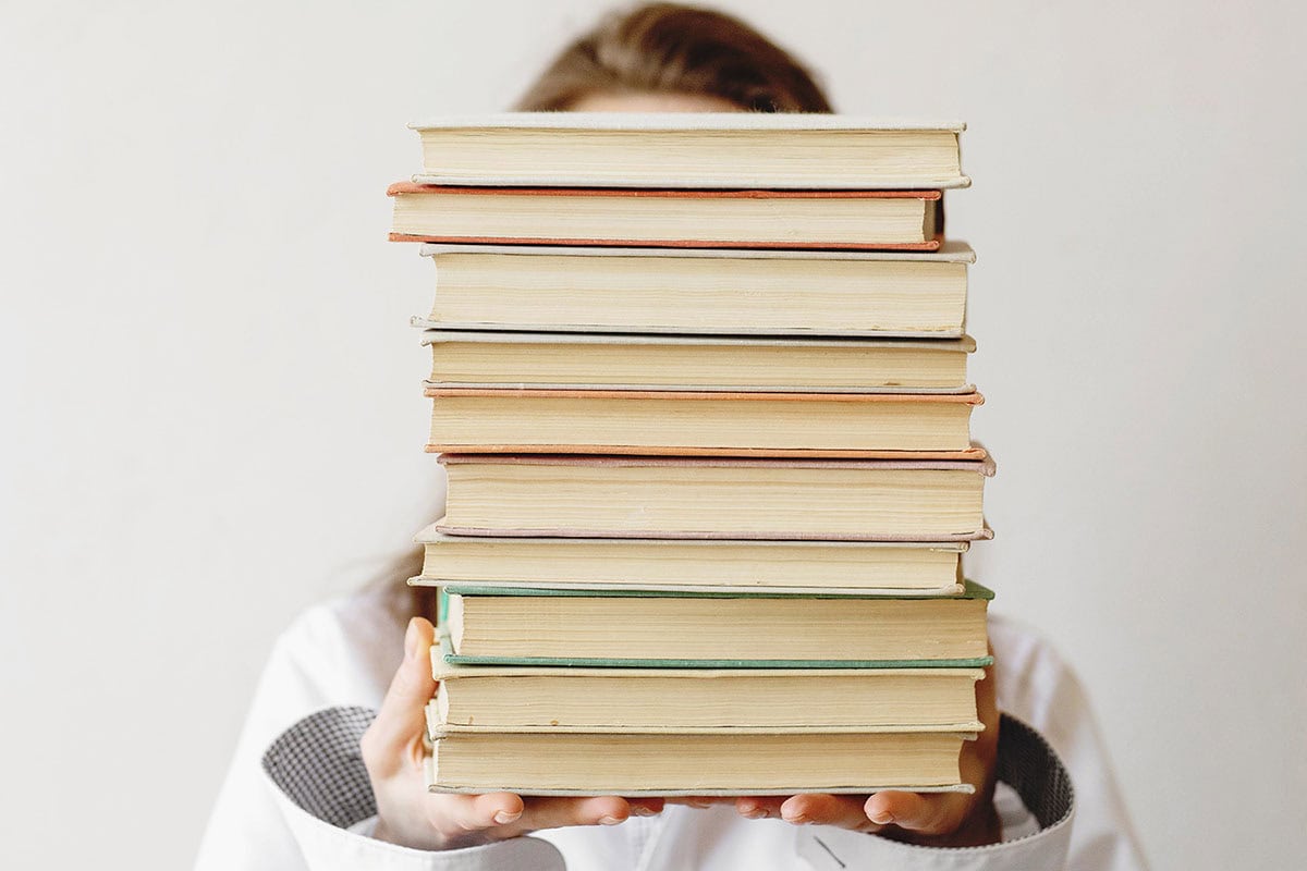 Woman holding a stack of books in front of her face