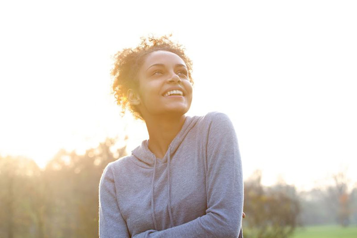 Questions Relationship 4 | Woman with dark, curly hair smiling in the sunlight