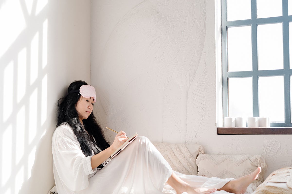 Woman writing in journal, wearing a sleep mask