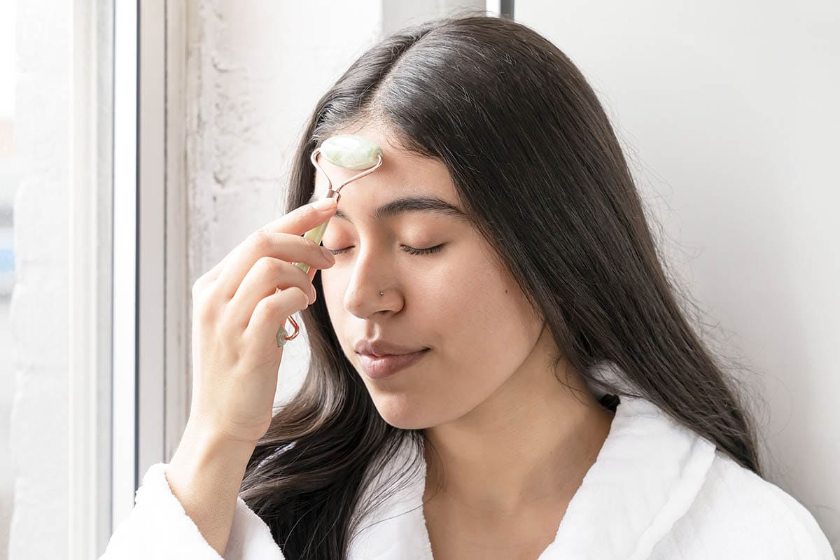 Woman using jade roller on her face