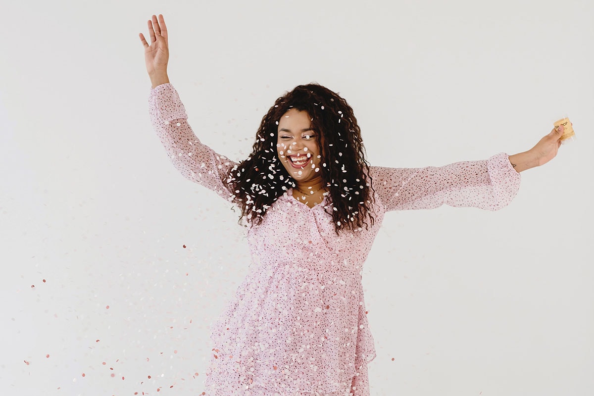Celebrate Yourself 2 | Dark, curly-haired woman throwing confetti in the air