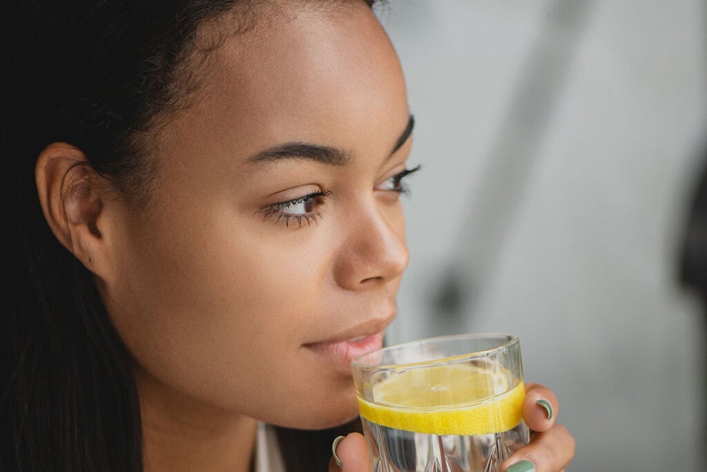 Woman looking reflective drinking glass of water