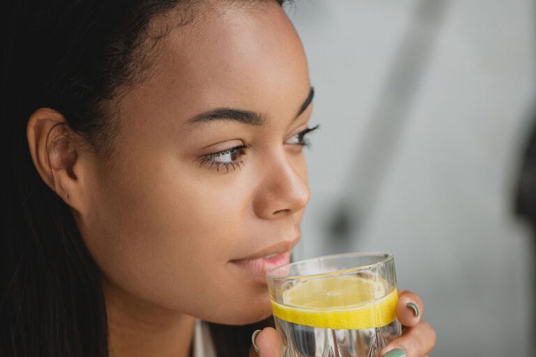 Woman looking reflective drinking glass of water