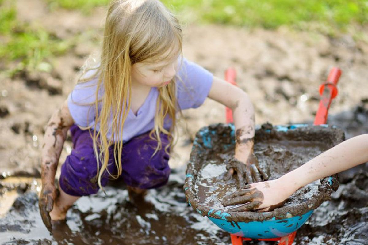 Young blonde girl playing in mud