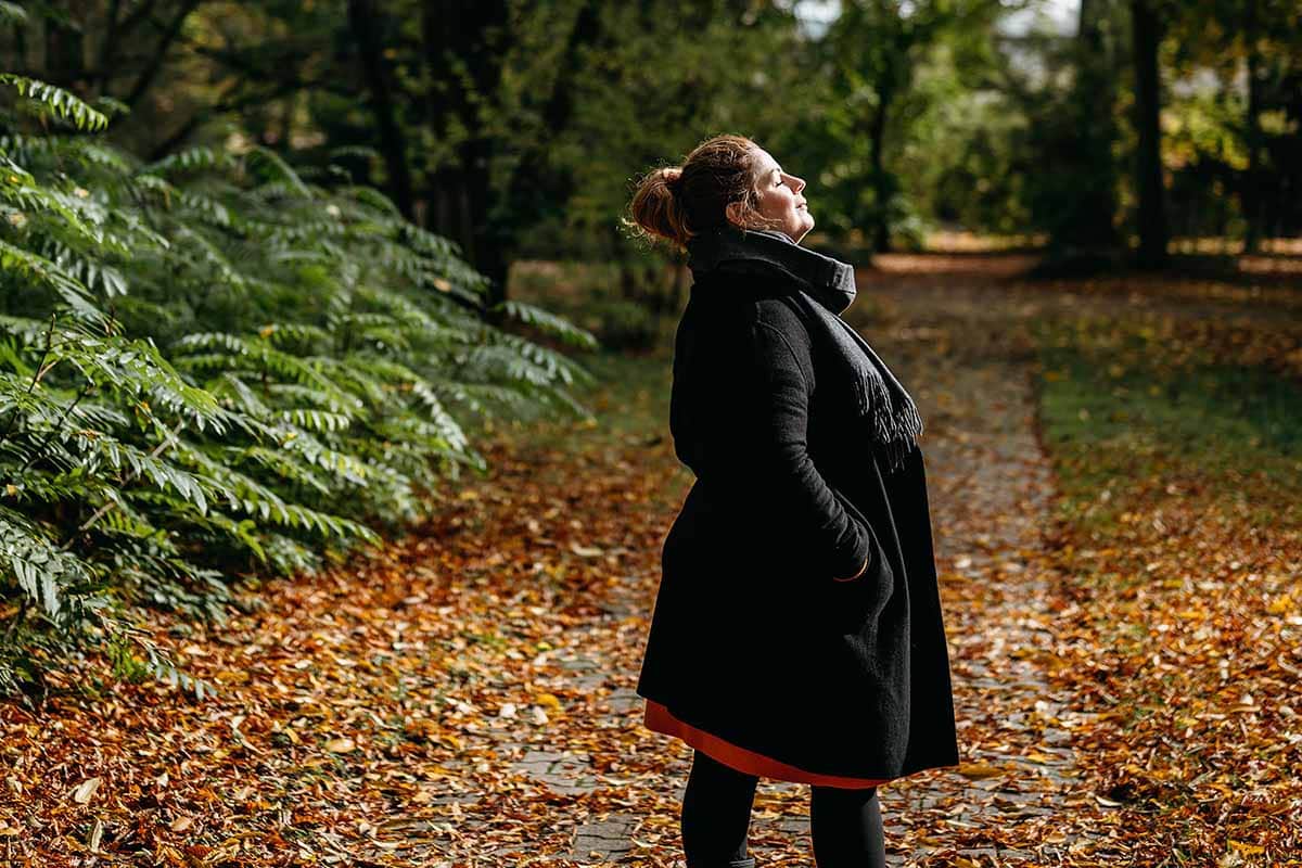 Woman soaking up the sunrays amongst fall landscape