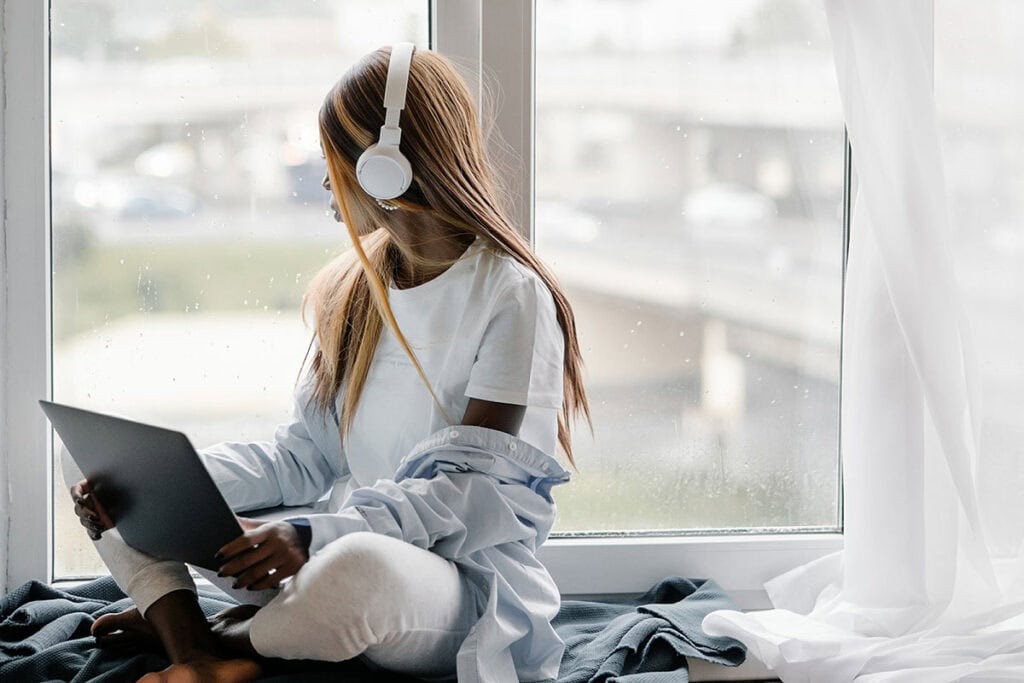 Woman sitting with headphones looking out large window