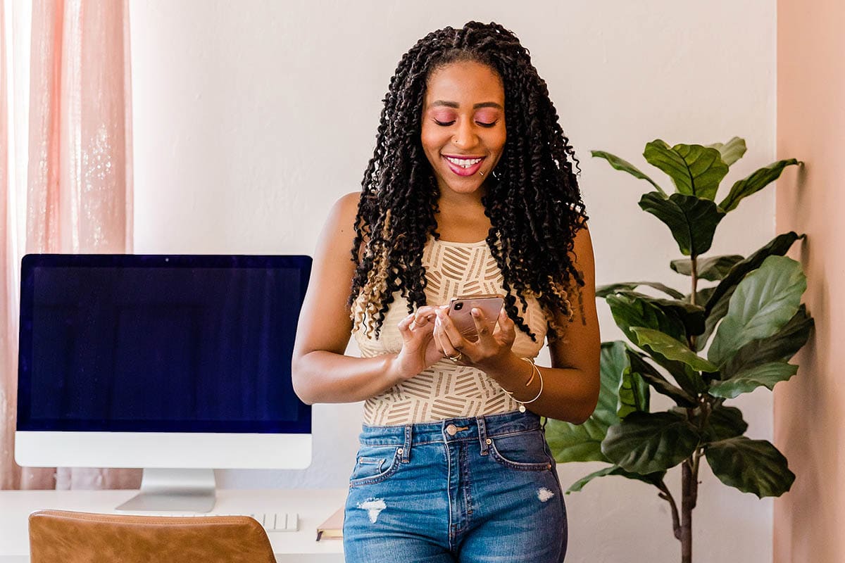 woman with curly hair smiling at phone